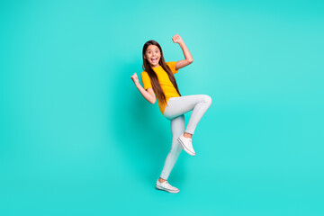 Full length photo of crazy kid girl raise fists standing isolated over teal color background