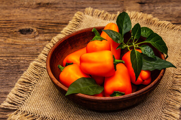 Ripe whole orange mini peppers in clay bowl
