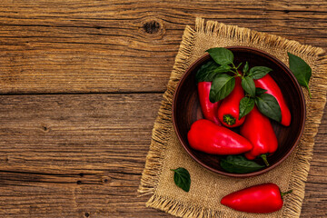Ripe whole red mini peppers in clay bowl