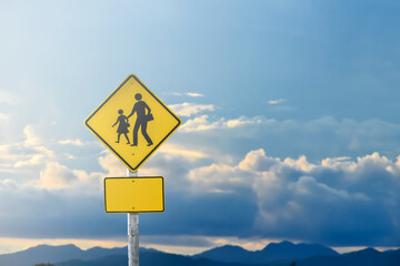 School zone sign on pole with cloudysky with the sunset.
