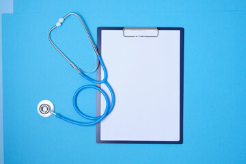 clipboard and stethoscope on blue background copy space top view