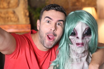 Surprised man taking a selfie with an alien 
