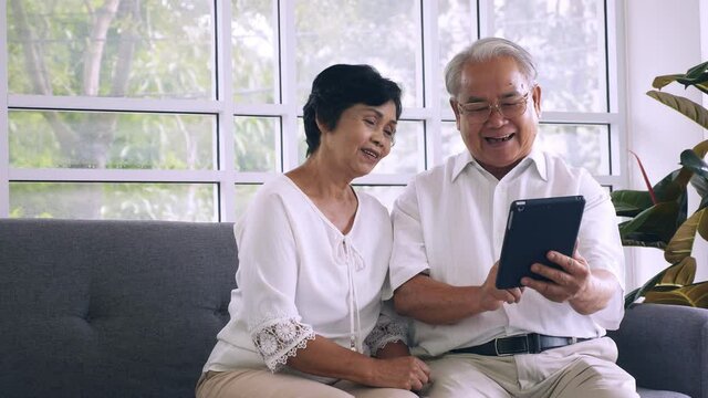 Asian elderly couple using tablet computer together at home.