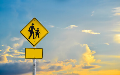 School zone sign on pole with cloudysky with the sunset.