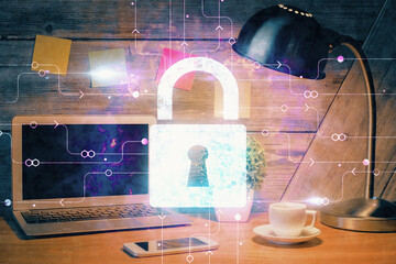 Double exposure of desktop with computer and lock icon hologram. Concept of data safety.