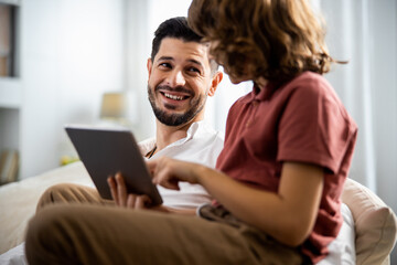 Father and son are sitting with a tablet