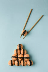 Korean food concept - rice balls with sesame seeds and nori seaweed, served with soy sauce, chopsticks on a bright blue background. Asian style. Top view with a copy space. Vertical orientation.