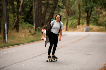 Fototapeta premium cheerful woman in white t-shirt riding skateboard with wakeboard in her hand.