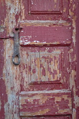 Peeled wooden red door close up.