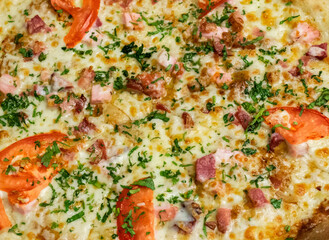 Close-up of pizza with ham, cheese, tomatoes and herbs and bacon. Food background