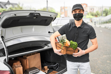 The courier in protective mask delivered the online order. Delivery of vegetables, food and pizza...
