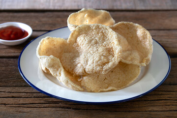 Fish Cracker in white dish Thai snack and tomato sauce on the old wooden table