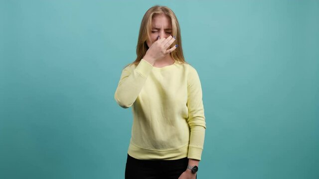 Caucasian girl that is showing disgust, pinching her nose to avoid bad smell. Negative emotions, nasty feelings.