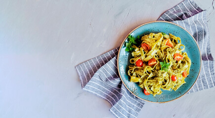 Fettuccine pasta with pesto sauce. Basil and pine nuts on concrete background. Italian cuisine. Top view. Copy space. Top view.