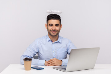 Happy successful businessman or top manager sitting in office workplace with saint angelic halo on...