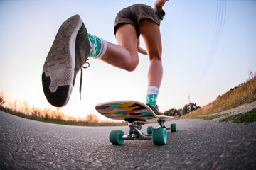 low angle view of girl who is riding on skateboard on the asphalt. - obrazy, fototapety, plakaty