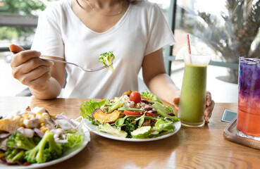 Selective focus of woman with Broccoli and salad which she make a Intermittent fasting with a Healthy food of salad and detox drink ,Healthy lifestyle Concept. - obrazy, fototapety, plakaty