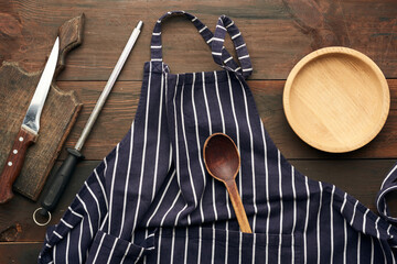 blue textile kitchen apron with white stripes and kitchen utensils, top view