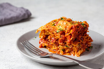 Portion of traditional Italian lasagna with meat and cheese on gray plate. Italian cuisine concept.