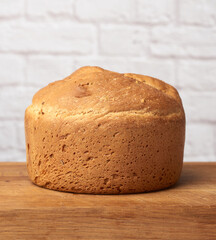 baked round bread in an electric bread maker on a wooden board