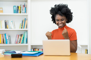 Cheering african american young adult woman at computer