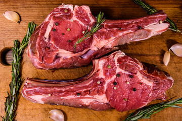 Raw ribeye steak, spices and rosemary on cutting board. Top view