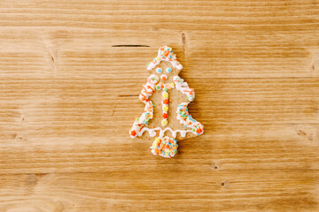 Christmas cookies decorated with icing and sprinkles on a wooden texture.