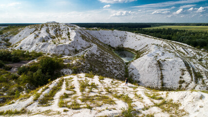Lake with blue transparent water in the white mountains. Deserted hills are formed from chemical wastes of phosphogypsum. Pollution of nature