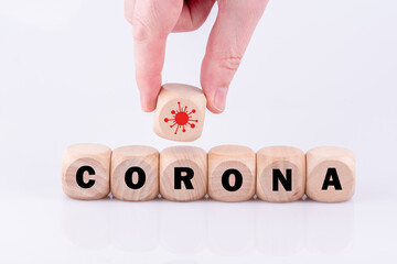 Das Wort CORONA mit einem Symbol eines Virus von einer Hand gelegt