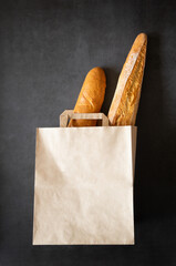 Two baguettes are in a paper bag with handles. Protecting the environment through the use of paper bags