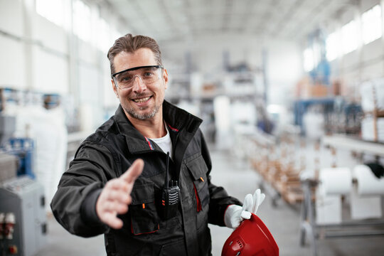 Portrait of factory worker. Man handshake in factory...
