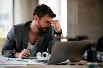 Obraz premium Young businessman working on projects. Tired businessman in suit working in the office..