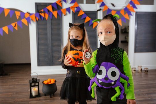 Children in Halloween costumes and with masks on their faces play