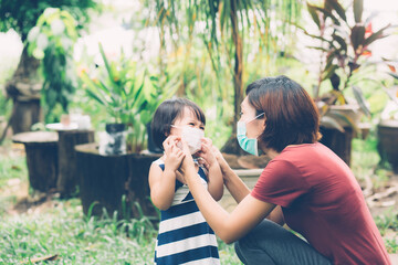 Mother take care daughter with face mask for protection disease flu or covid-19 outdoors, mom wearing on medical mask with child safety for protect outbreak of pandemic, medical concept.