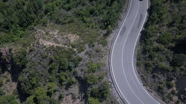 Vista a&eacute;rea de coche negro descapotable pasando por una curva de la carretera en la monta&ntilde;a