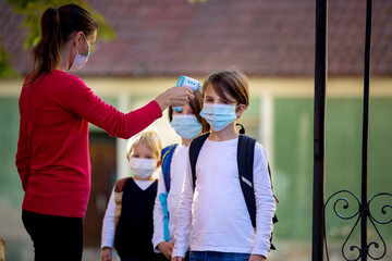 Teacher or medical person, controlling temperature and doing medical check at school for covid