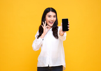 Happy young Asian woman showing at blank screen mobile phone and hand gesture ok isolated over...