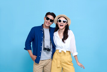 Happy playful Asian couple tourist dressed in summer clothes to travel on holidays isolated on blue background.