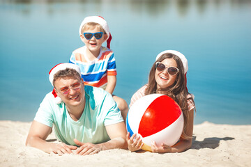 Christmas concept. Family wearing christmas caps at the beach