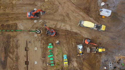 Große Baustelle: Mehrere Baumaschinen (Bagger, Radlader, Bulldozer, Walze, Betonmischer) auf engen...