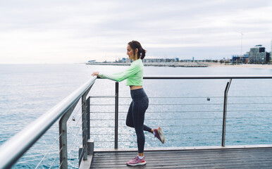 Sporty adult woman exercising on seafront