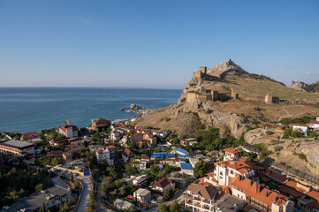 old castle in the mountains against the blue sky, old defensive fortress and modern houses near the fortress