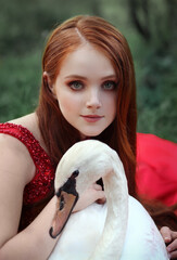 Close up portrait: beautiful red head young woman in red dress with white swan
