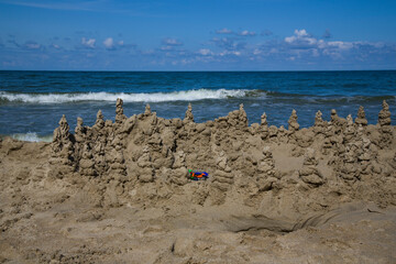 Fototapeta na wymiar Sand castle on the blue sea. Beach games