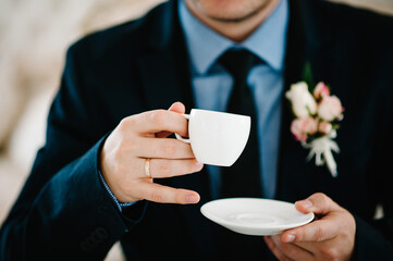 Man holds cup with coffee and enjoys. Business man drinking a coffee at the cafe.