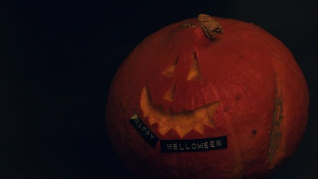 Slowly moving light over helloween pumpkin with engraved scary face, looping possible