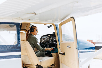 Woman pilot in private plane cockpit, wearing headset with microphone. © Bostan Natalia