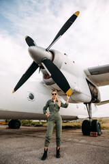 Woman pilot wearing uniform, standing in front of an airplane propeller.