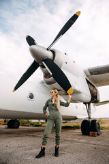 Woman pilot wearing overall, standing in front of an airplane propeller.
