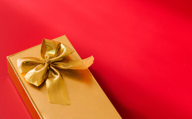 Gold color gift wrap with gold bow on red background